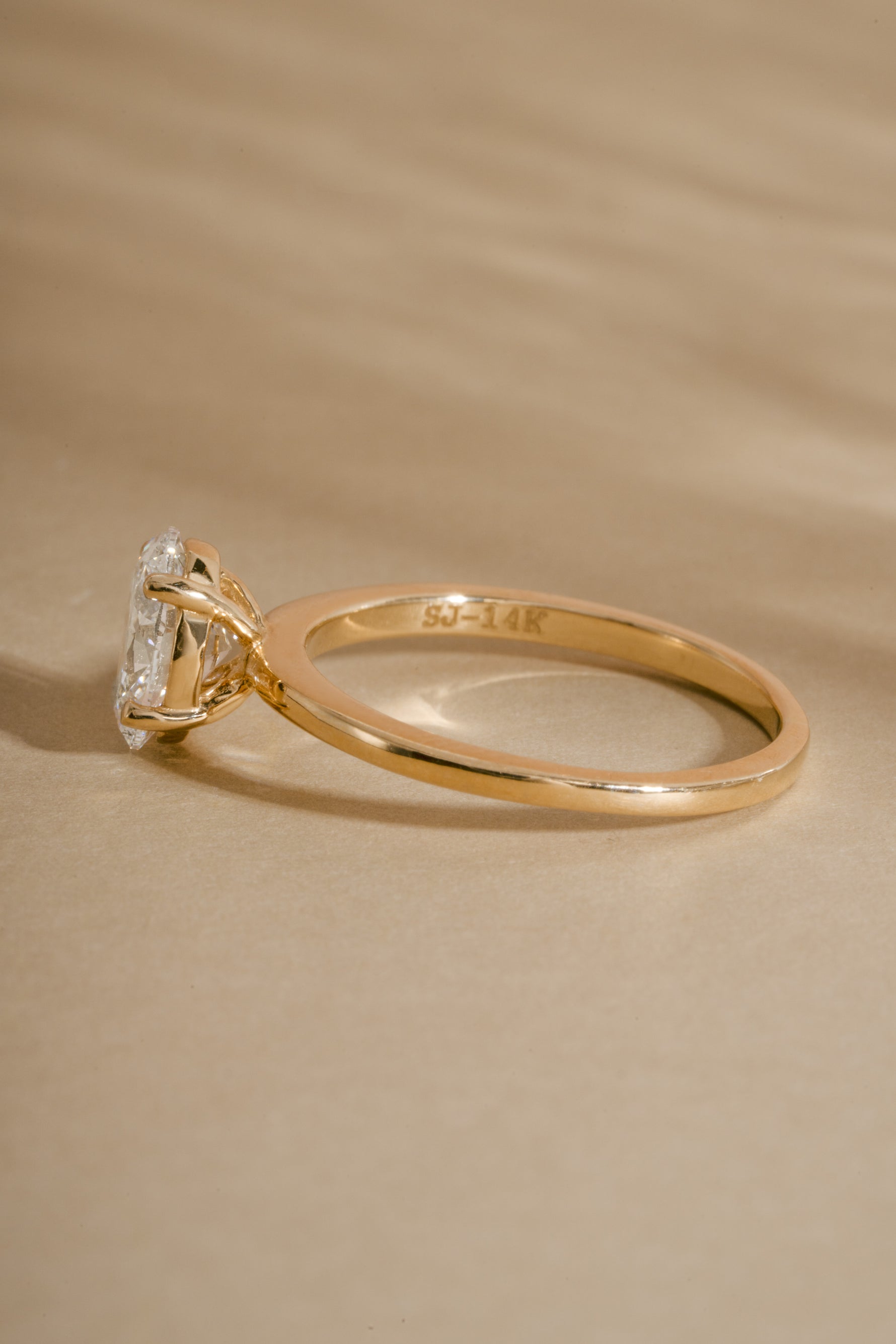 Side view of 14K solid gold oval cut engagement ring on neutral background