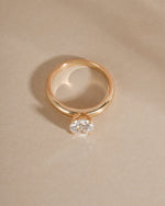 Fine jewelry gold ring with a lab grown diamond on a beige background