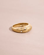 Side view of solid 14k gold star dome ring with celestial design and lab grown diamonds on light pink background