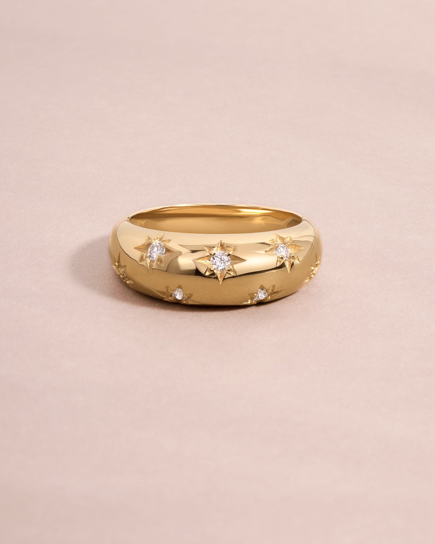 Sculptural 14k gold dome ring with star details and lab grown diamonds on light pink background