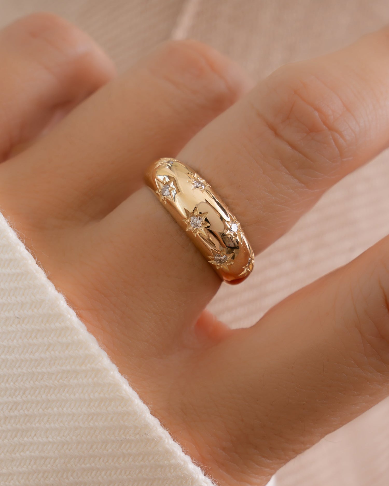 Solid 14k gold star dome ring worn on hand with white background