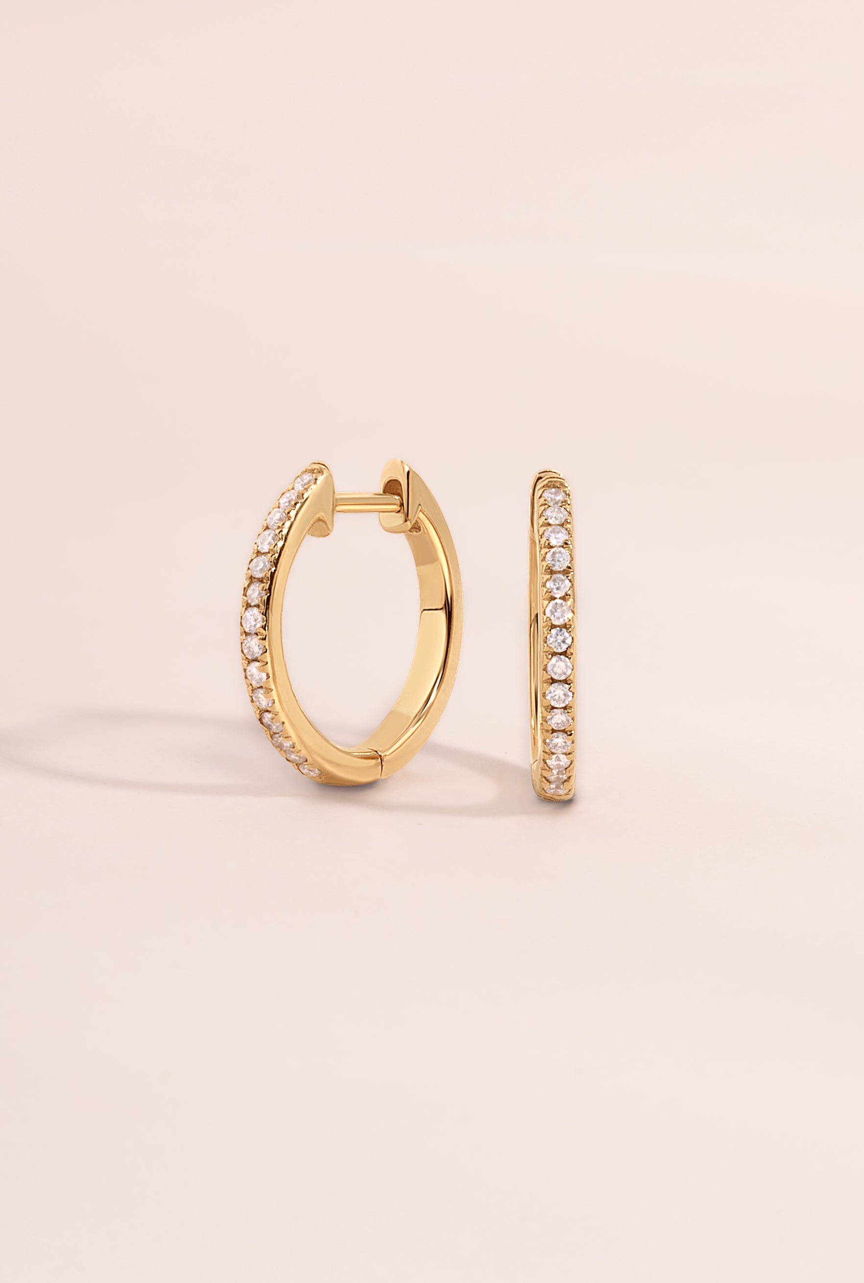 Side view of 14K solid gold pavé lab-grown diamond huggie earrings by Sami Jewels on a neutral background.