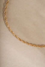 Close-up of a 14K solid gold twisted rope chain bracelet on neutral background