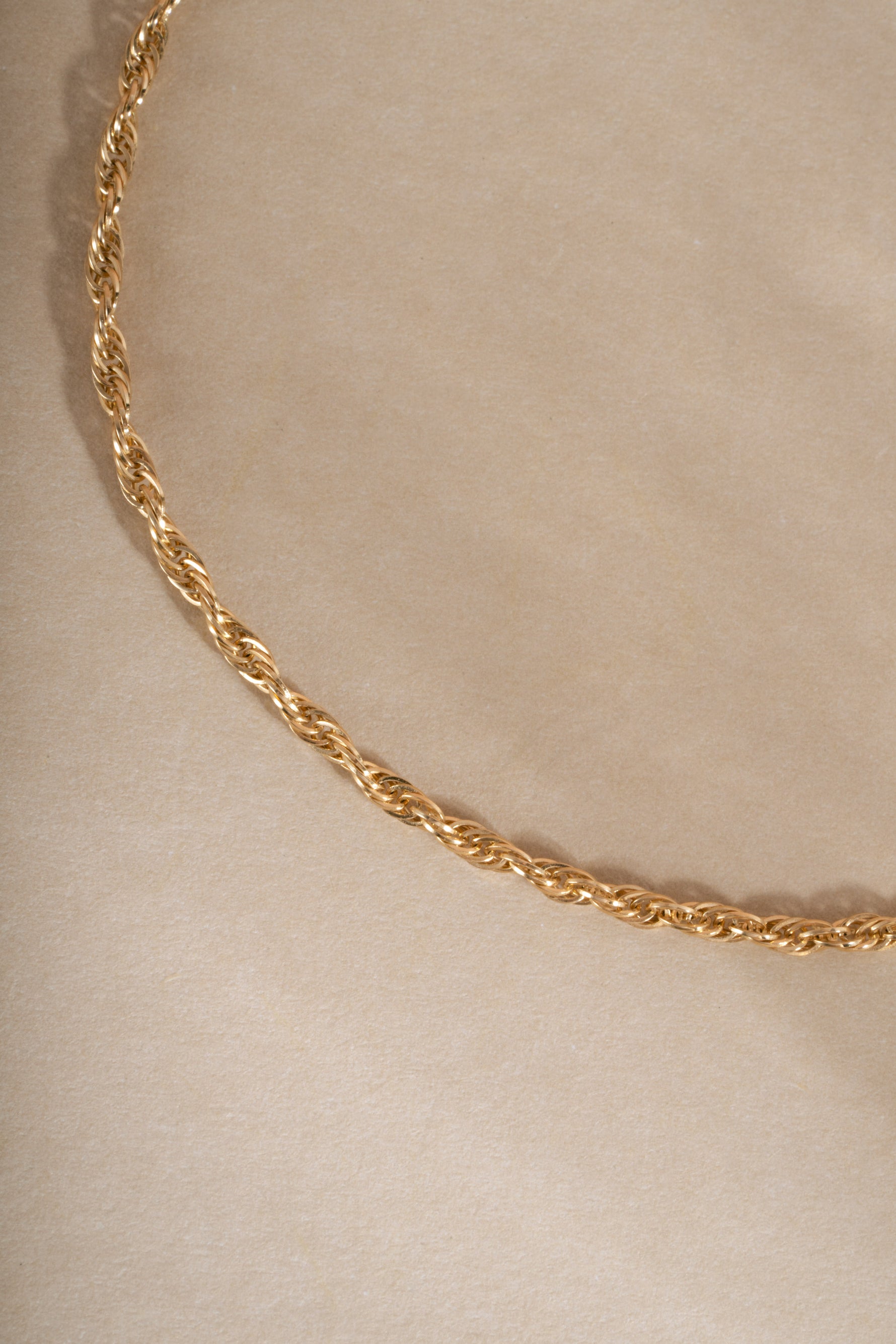 Close-up of a 14K solid gold twisted rope chain bracelet on neutral background