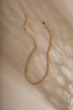 Fine 14K solid gold twisted rope chain bracelet with lobster clasp and extension chain detail on neutral beige background
