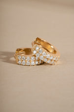 Pair of lab grown diamond huggie earrings on neutral background