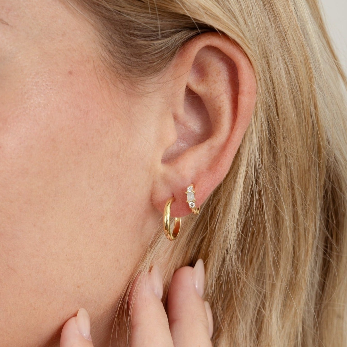 model wearing gold hoop earrings with diamond huggies