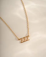 Close-up of Sami Jewels gold angel number 222 necklace, showcasing a delicate pendant on a fine chain.