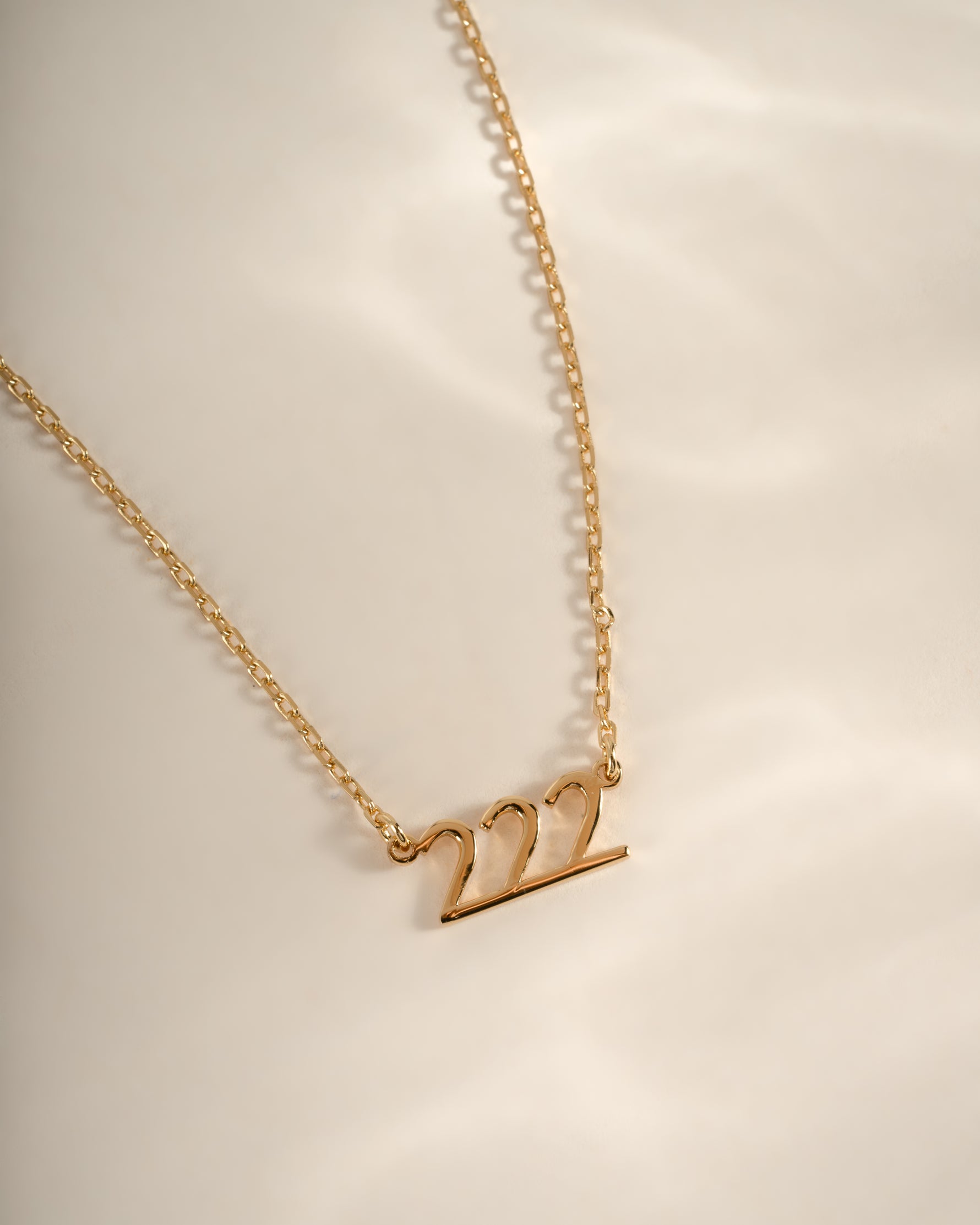 Close-up of Sami Jewels gold angel number 222 necklace, showcasing a delicate pendant on a fine chain.