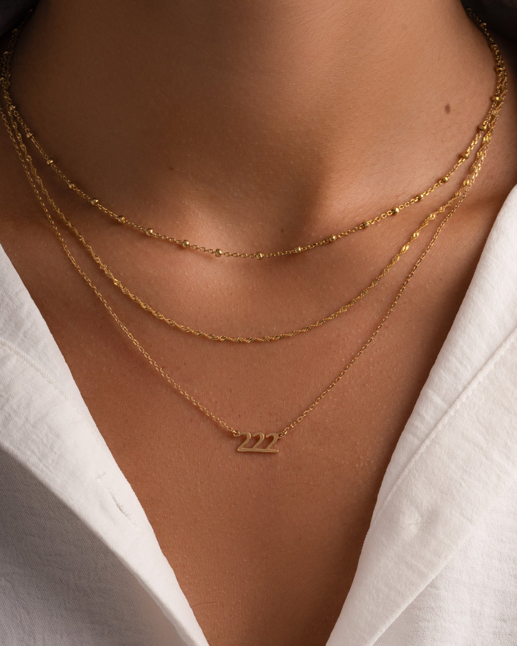Gold angel number 222 necklace by Sami Jewels styled on a model, showcasing a delicate pendant on a chain.