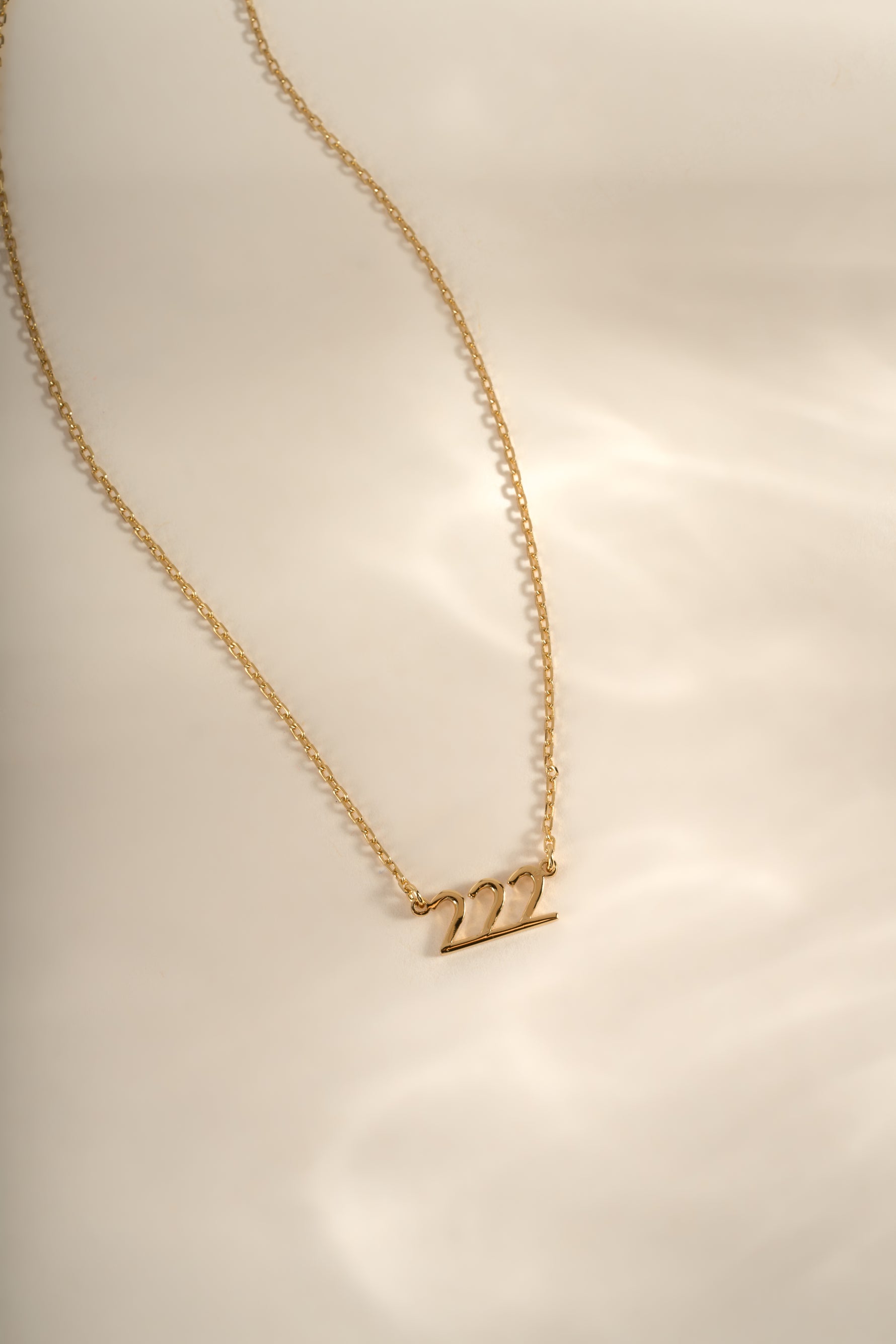 Gold angel number necklace featuring the number 222, designed by Sami Jewels, showcasing a delicate chain and pendant.
