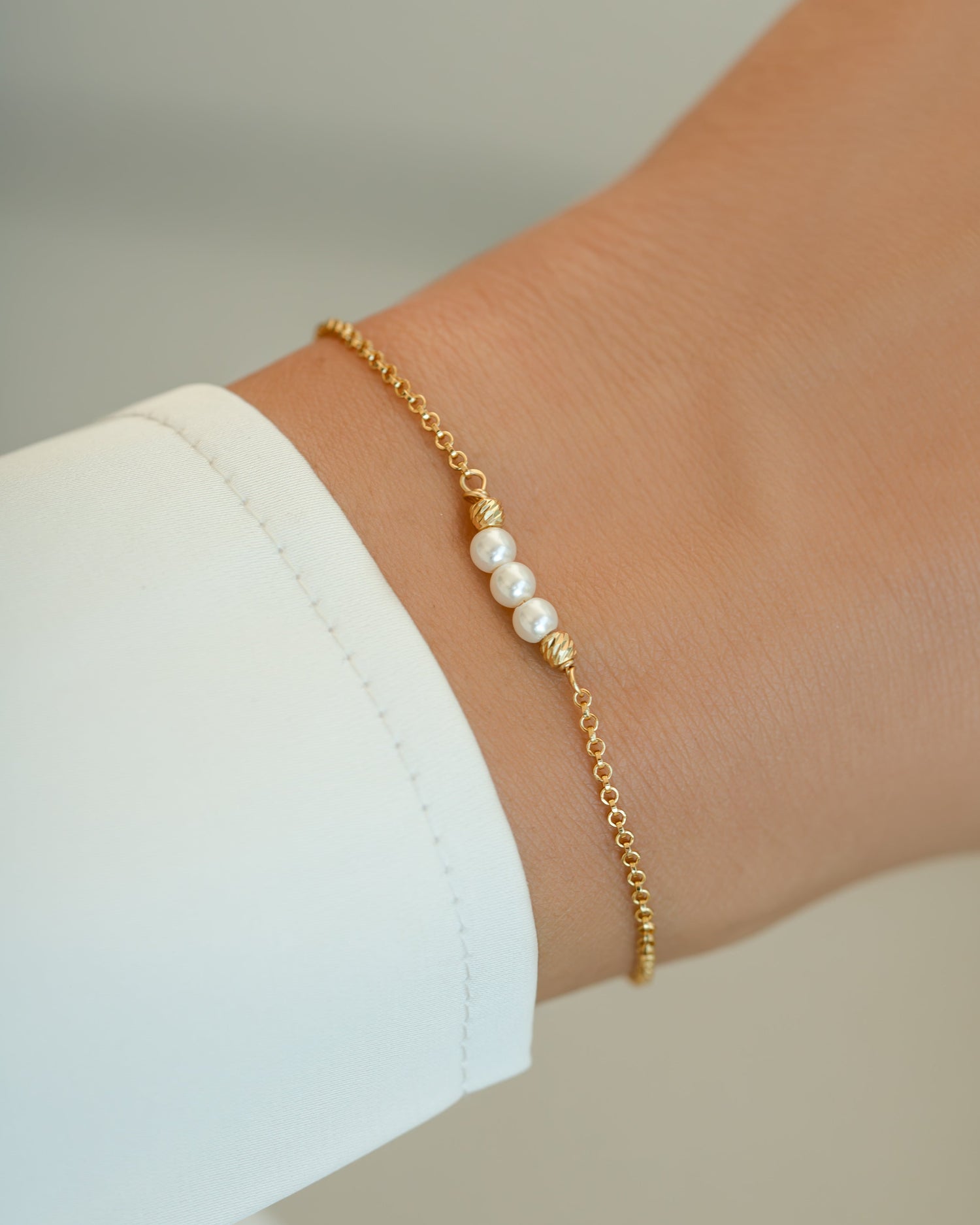 Elegant Sami Jewels 3 Pearl Bracelet showcasing three white pearls on a gold bracelet against a model.