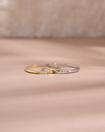 3 stone cubic zirconia stacking rings in gold and sterling silver on neutral background