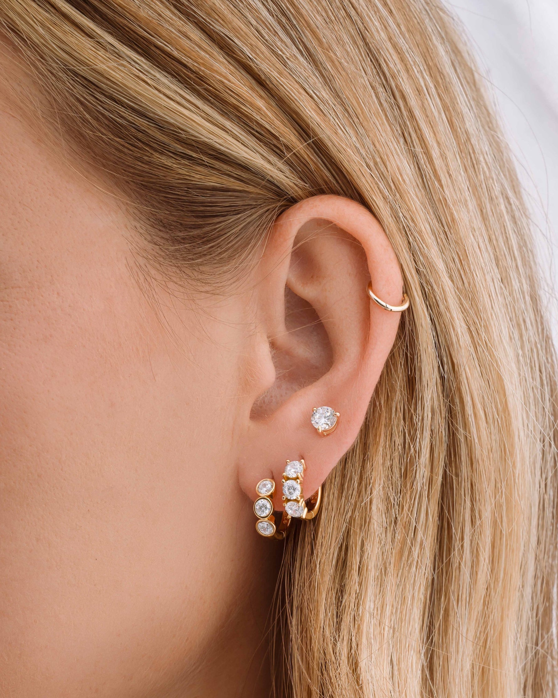 Gold Sami Jewels Bella 3 Stone Huggie Hoop Earrings featuring three sparkling stones and a sleek, modern hoop design.