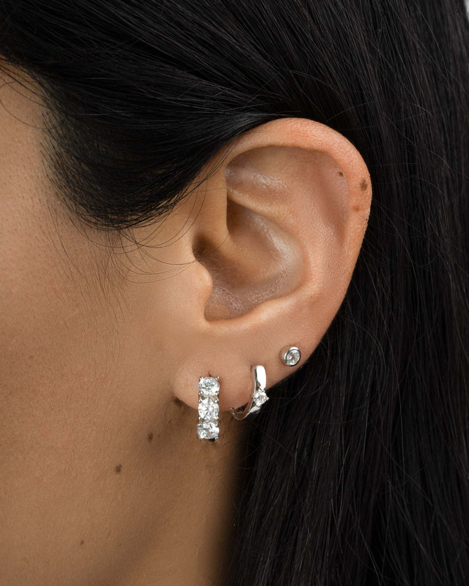 Sterling silver Bella 3 Stone Huggie Hoop Earrings by Sami Jewels, featuring three sparkling stones on small, stylish hoops.