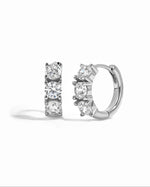 Sterling silver Bella 3 Stone Huggie Hoops earrings with three sparkling stones on a white background.