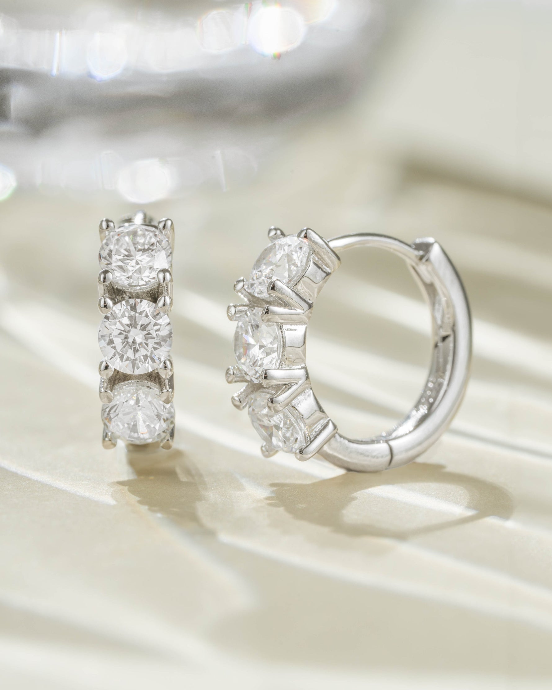 Sterling silver Bella 3 Stone Huggie Hoops earrings featuring three sparkling stones and a secure hoop design.