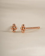 Rose gold 4-ball stud earrings by Sami Jewels, small round earrings with sleek ball design, shown from an angled view.