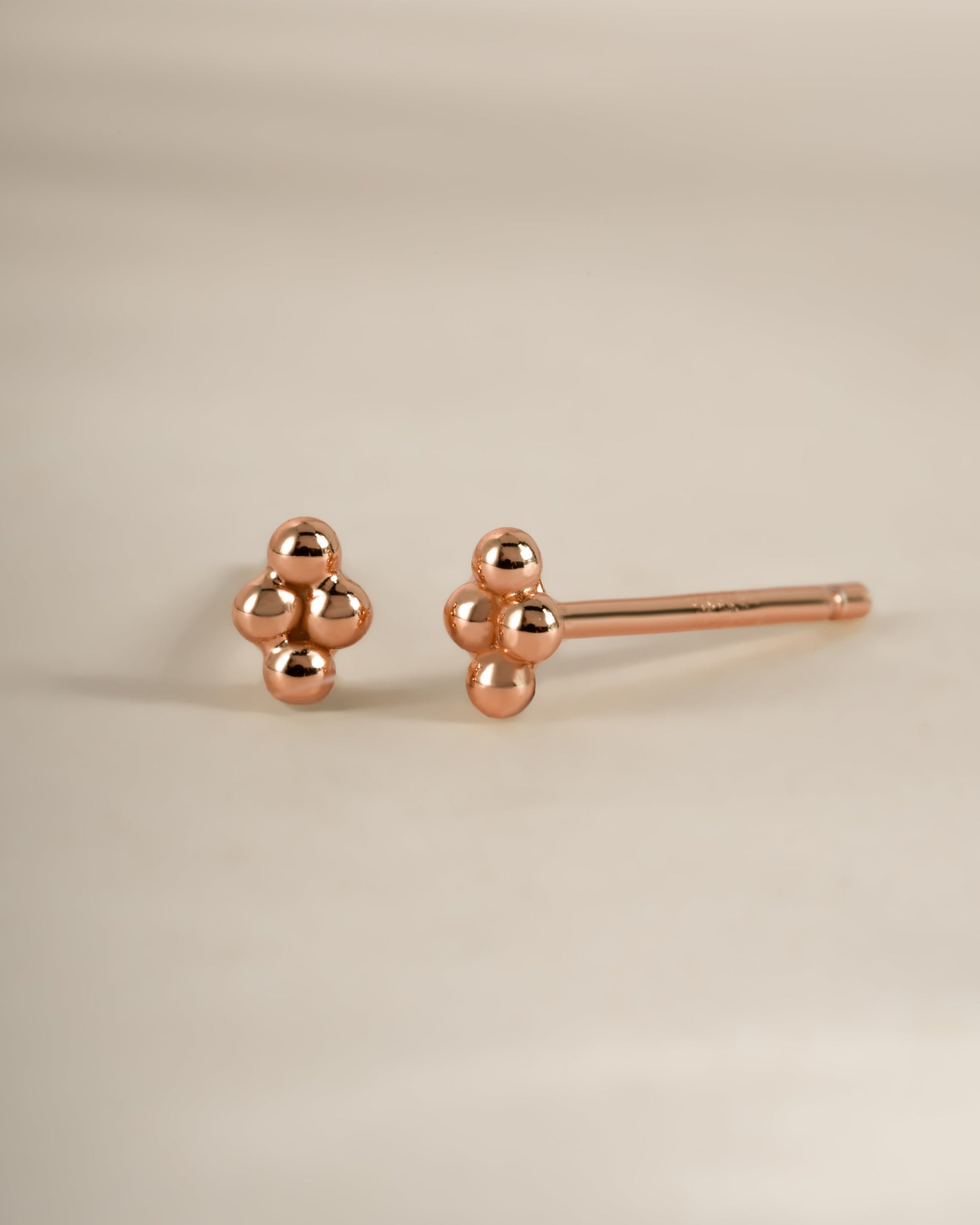 Rose gold 4-ball stud earrings by Sami Jewels, small round earrings with sleek ball design, shown from an angled view.