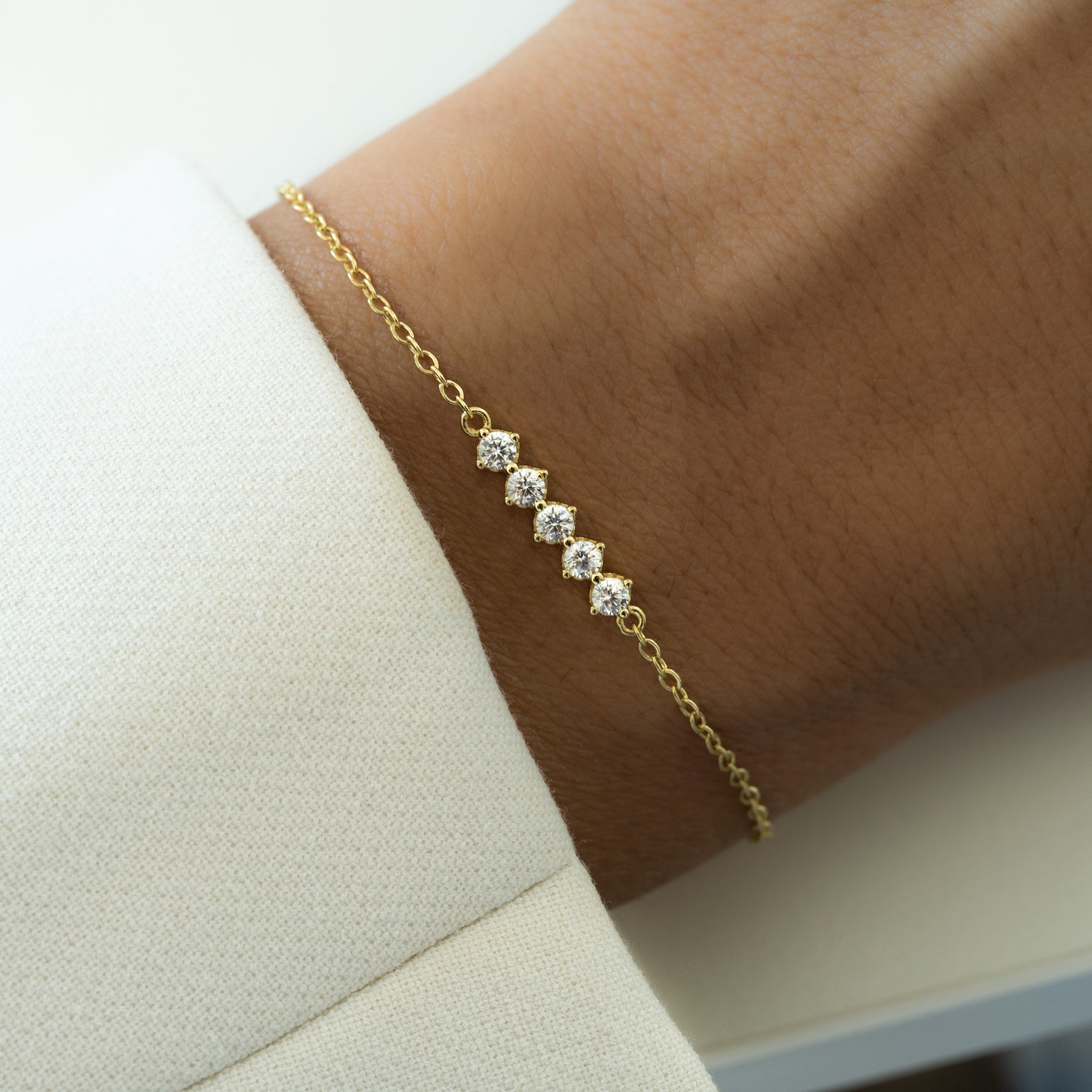 model wearing a gold diamond bracelet with 5 cubic zirconia stones