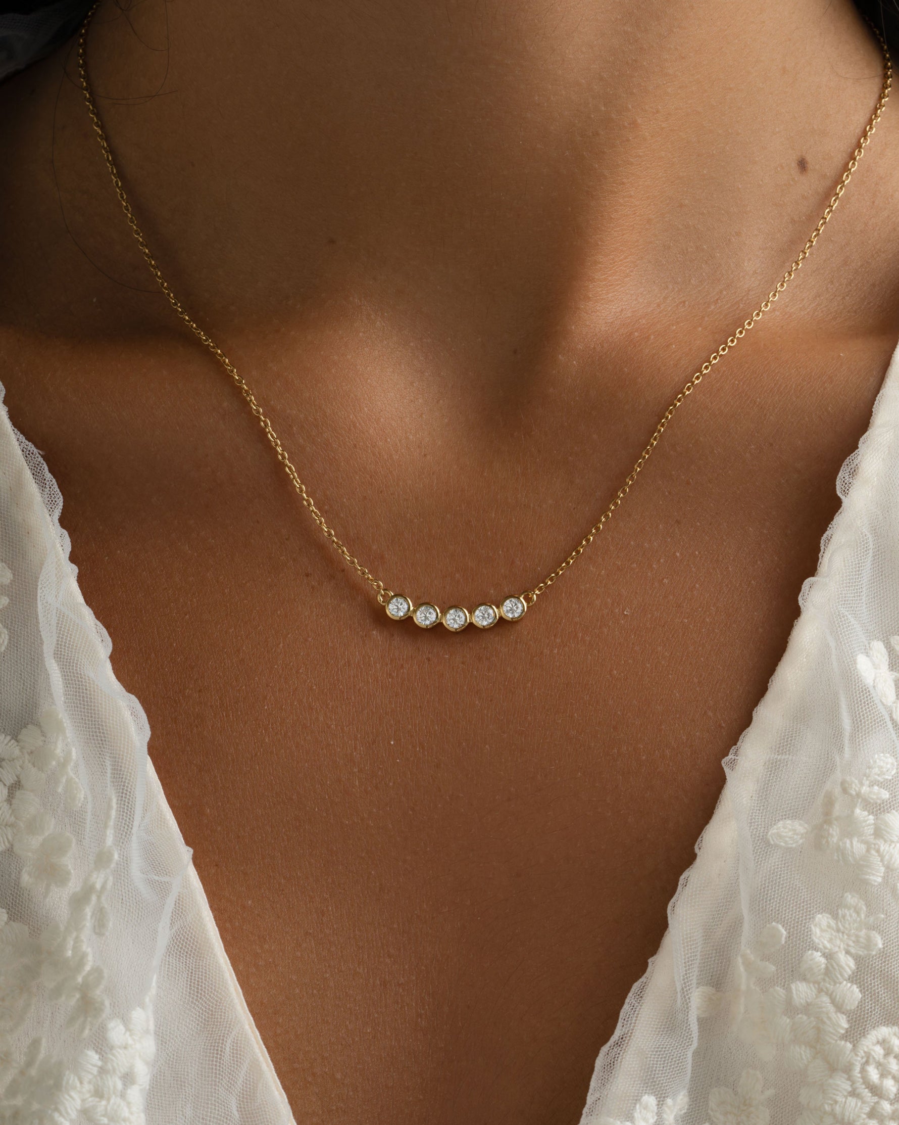 Gold five-stone diamond necklace by Sami Jewels, showcasing a stylish bar design on a model.