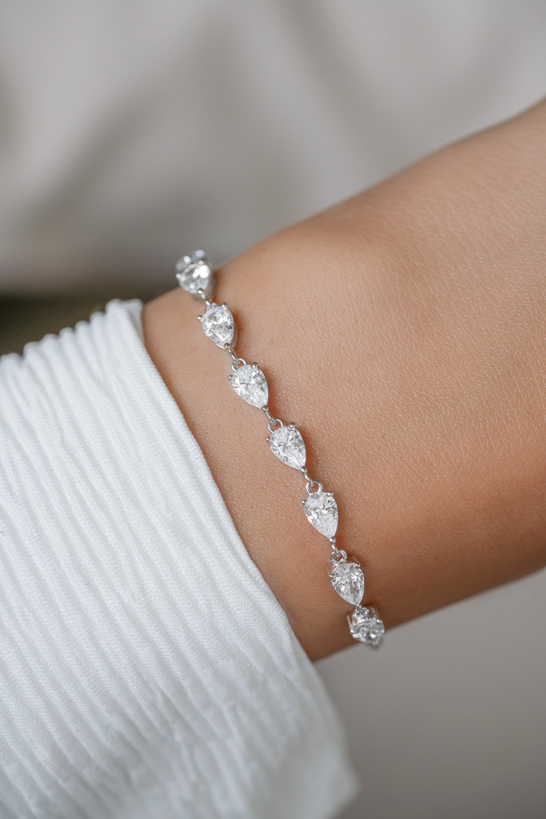 A close-up of a silver-toned half tennis bracelet with pear cut cubic zirconia stones set on a wrist