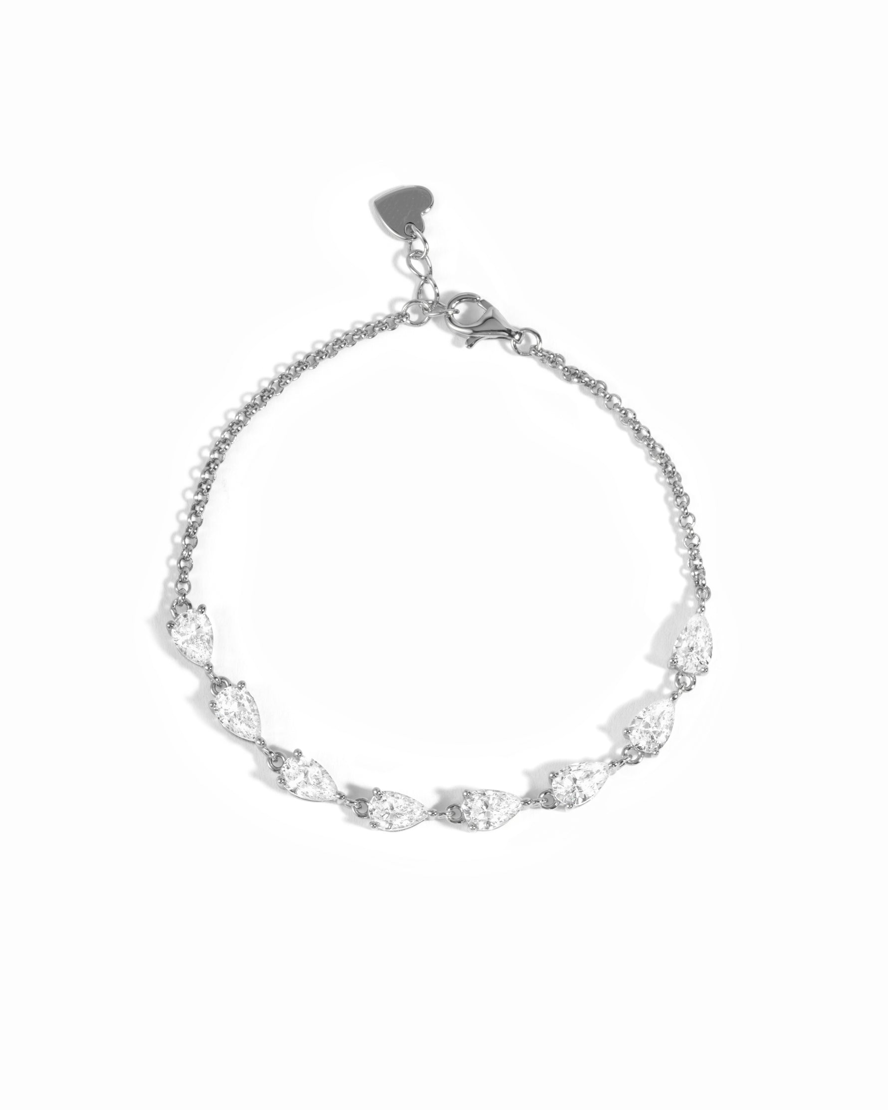 A delicate silver chain bracelet featuring a row of pear-cut clear stones and a small heart-shaped charm at the clasp, shown on a plain white background.