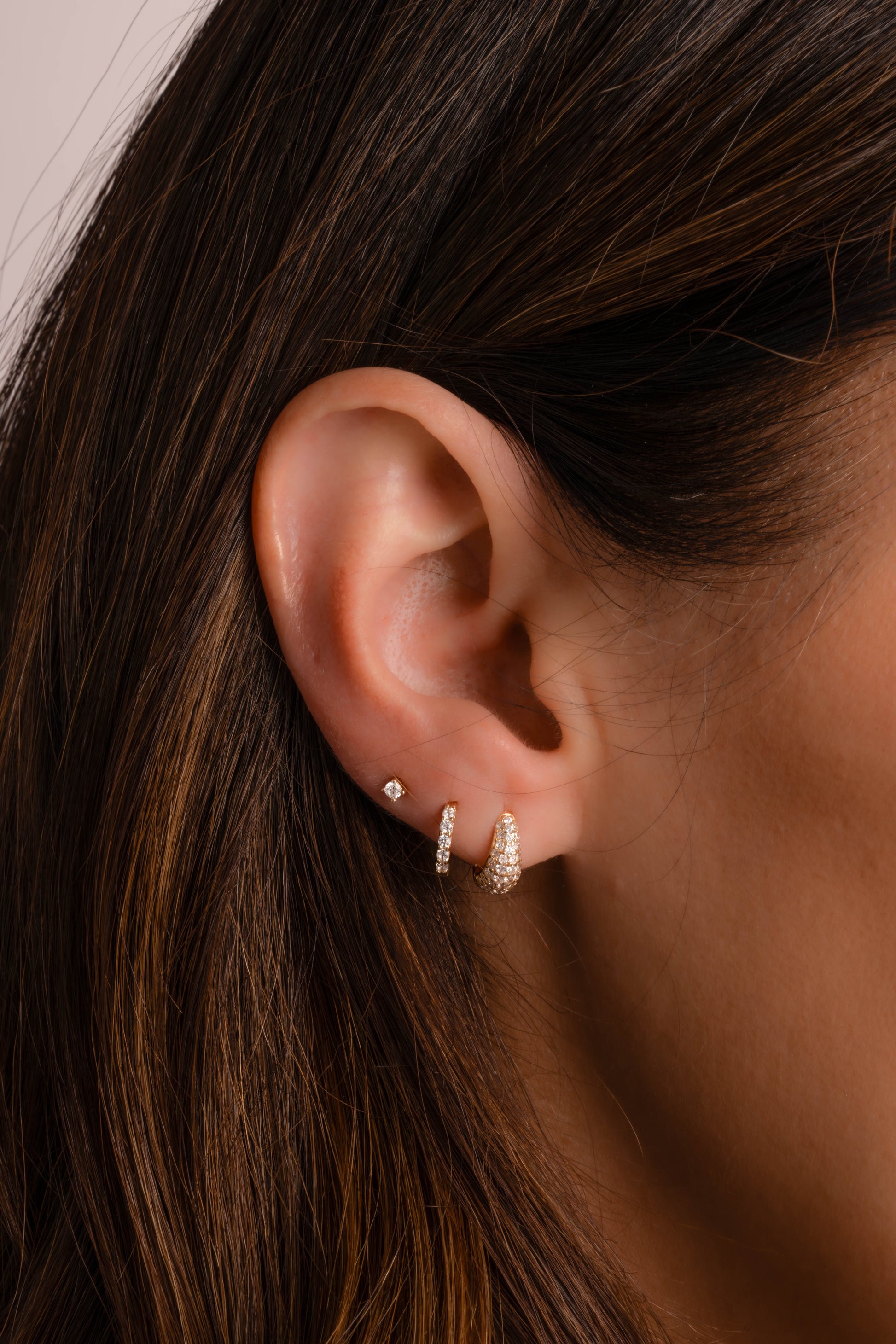 Model wearing stud earrings, pave huggie hoop earrings, and 10mm pave diamond huggies