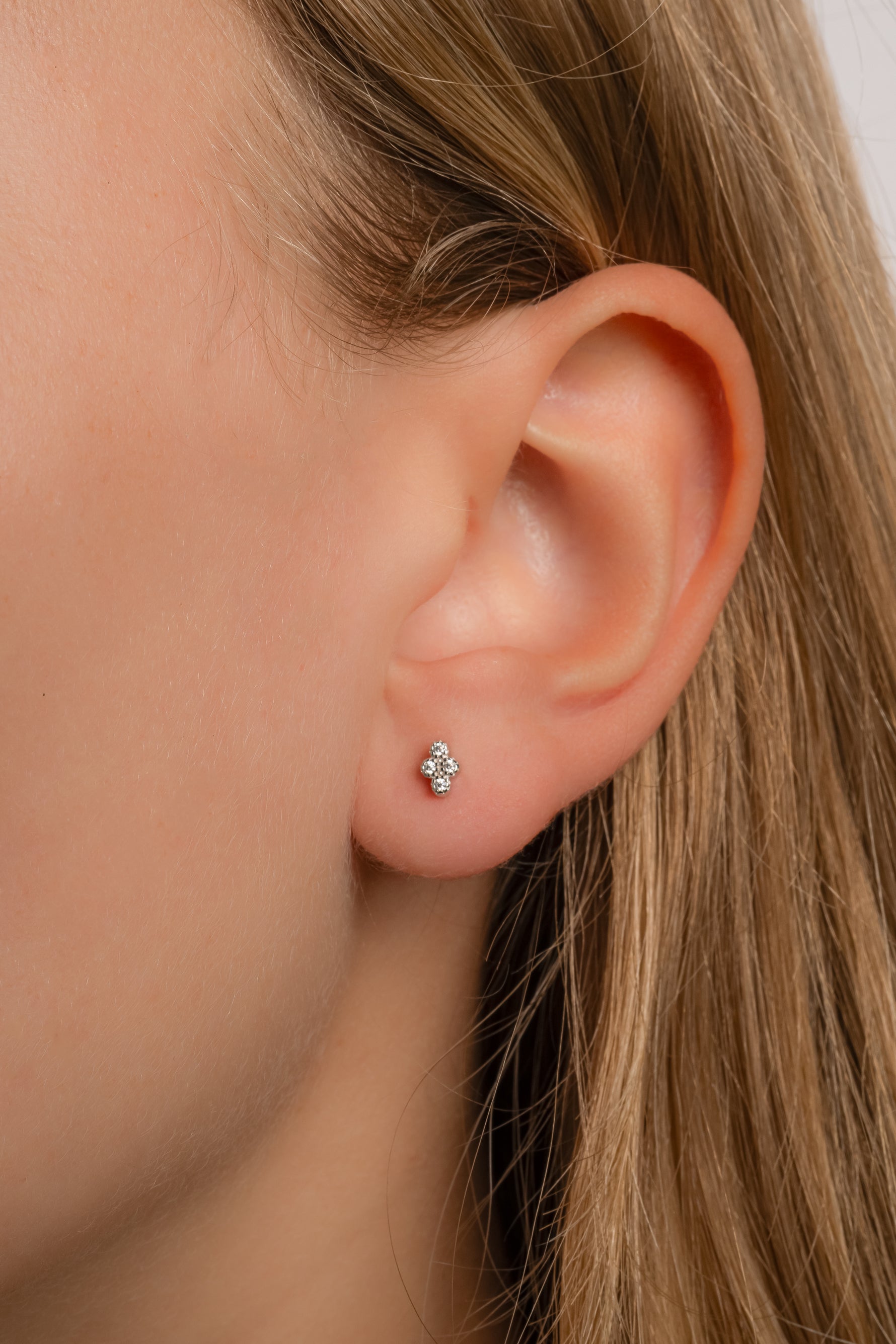 Model wearing sterling silver diamond shaped studs with 4 diamond stones. 