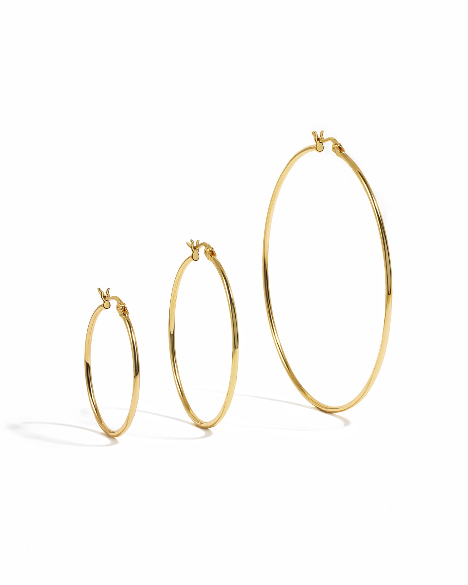 closeup image of gold hoops on a white background, these simple hoop earrings come in three sizes, 30mm, 40mm, or 60mm
