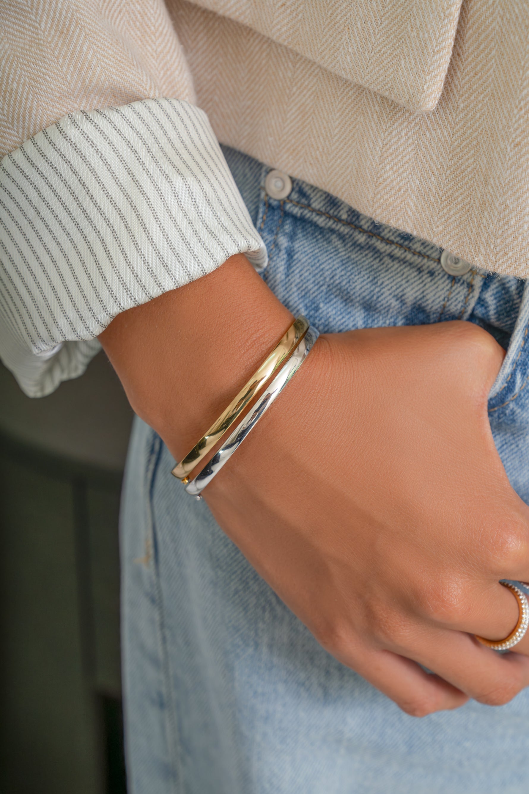 Model wearing gold and silver sleek plain bangles stacked for a mixed metals look.