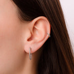 Model wearing delicate twisted hoop earrings in silver