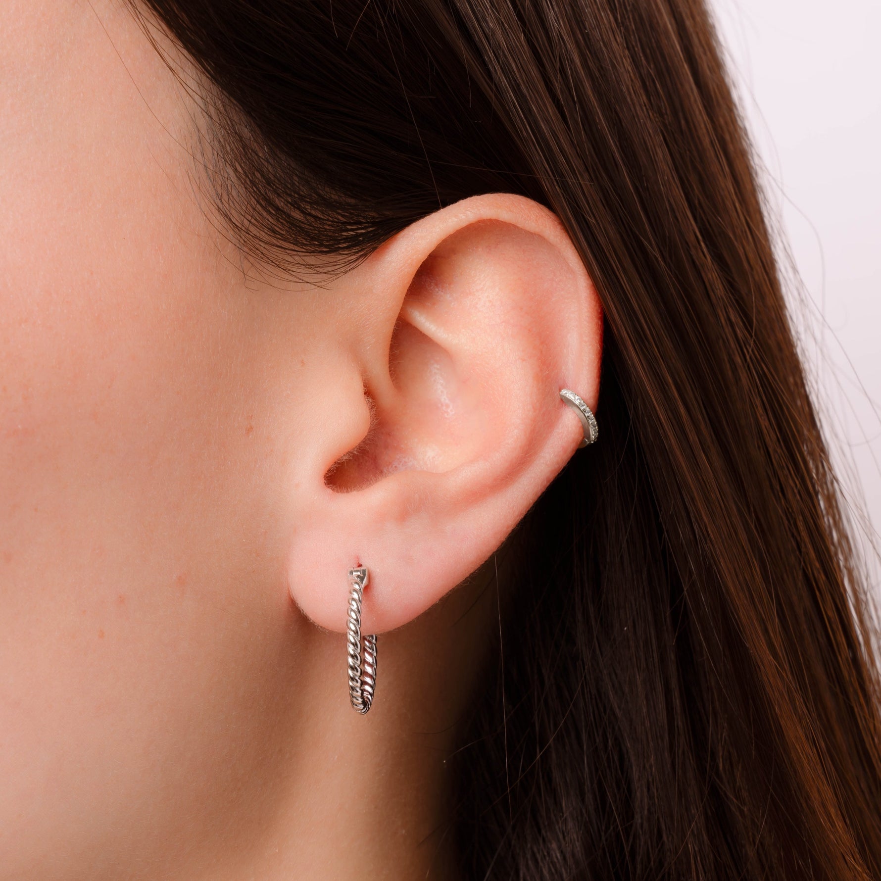 Model wearing delicate twisted hoop earrings in silver
