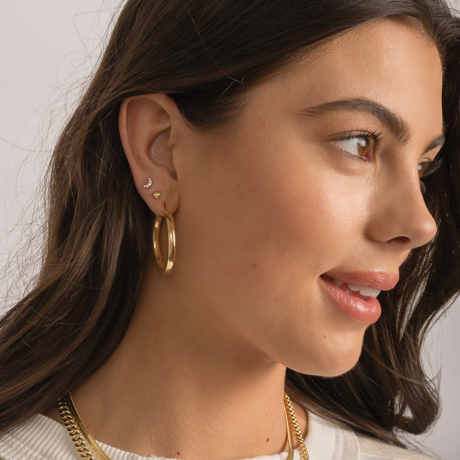 Model wearing jlo hoops, dot studs, and moon stud earring stack.