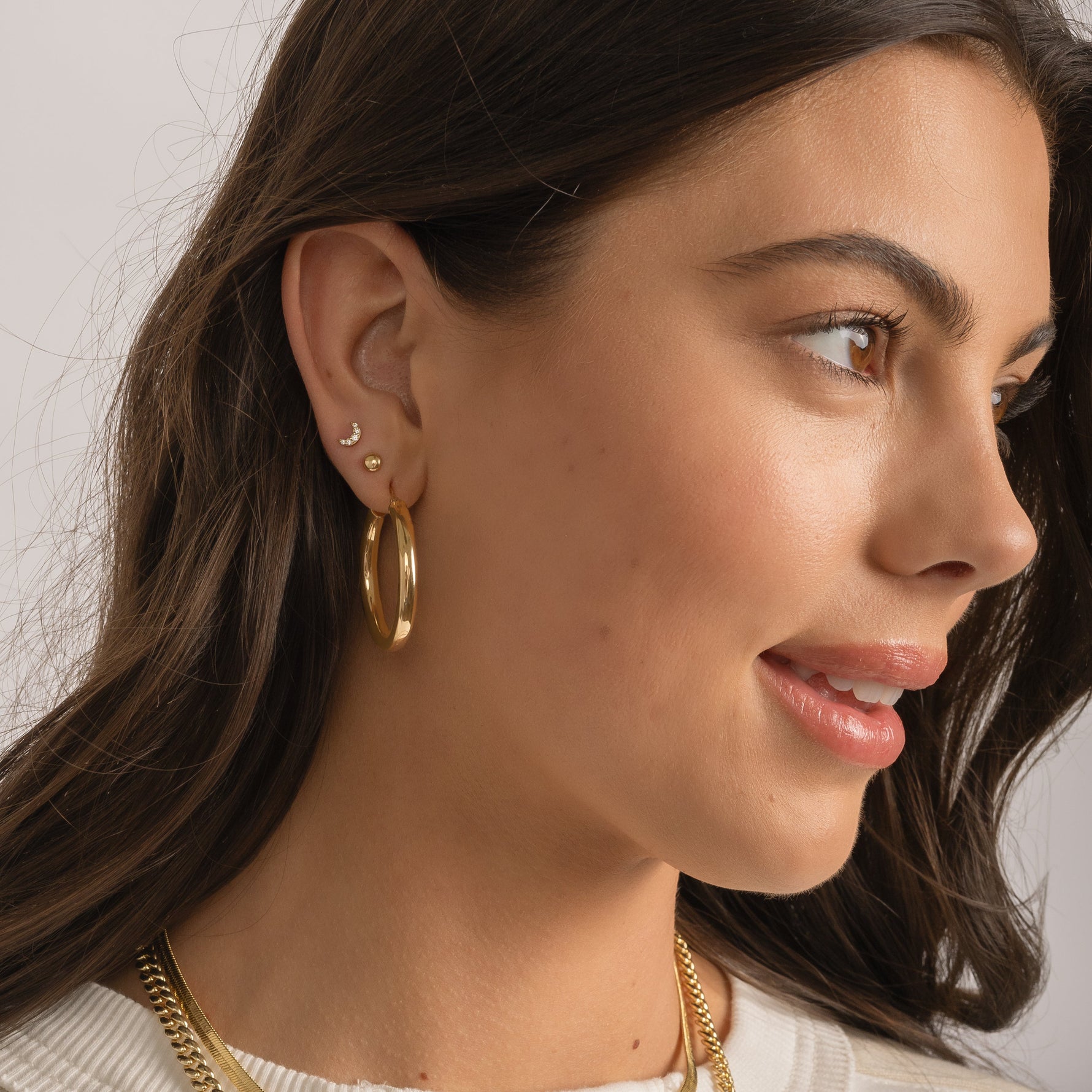 Model wearing jlo hoops, dot studs, and moon stud earring stack.