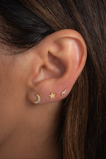 Gold celestial stud earrings in models ear.