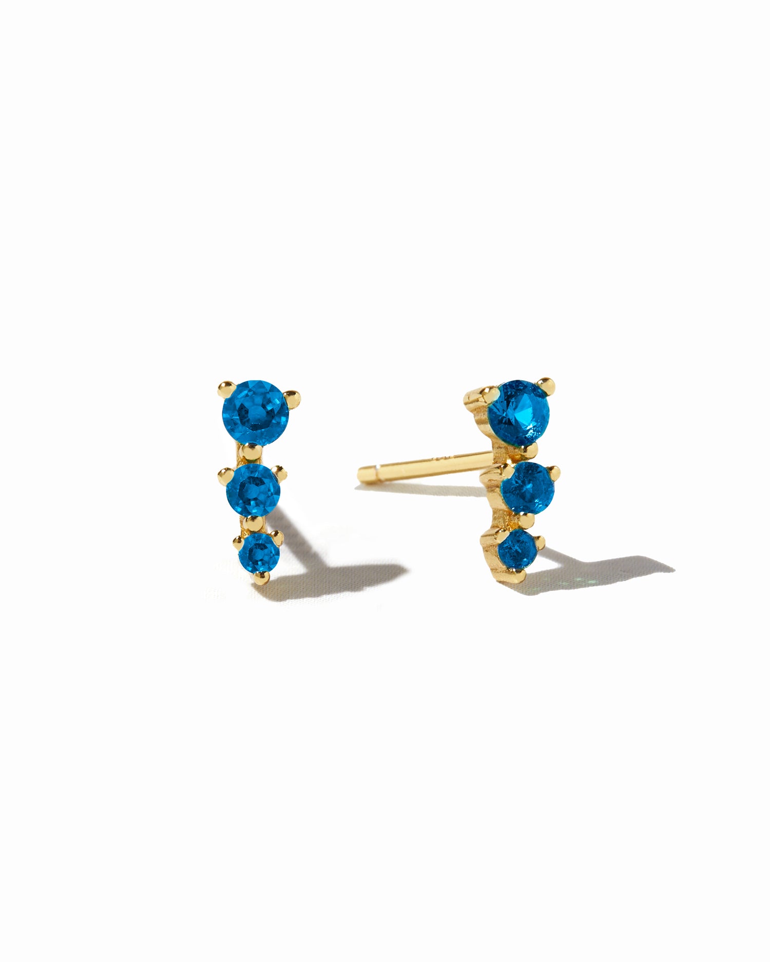 Gold ear climber studs with aquamarine stones.