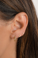 Model wearing moon stud earrings with star-studded diamond hoops and a solitaire diamond stud.