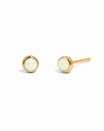 Gold earrings with opal stones on a white background