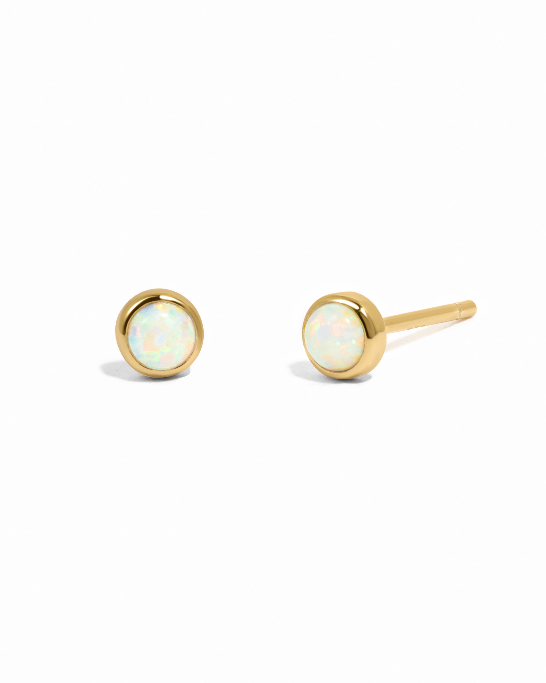 Gold earrings with opal stones on a white background