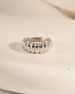 Chunky sterling silver fluted statement ring on a textured surface.