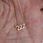 Model holding gold 222 lucky angel number necklace in hand