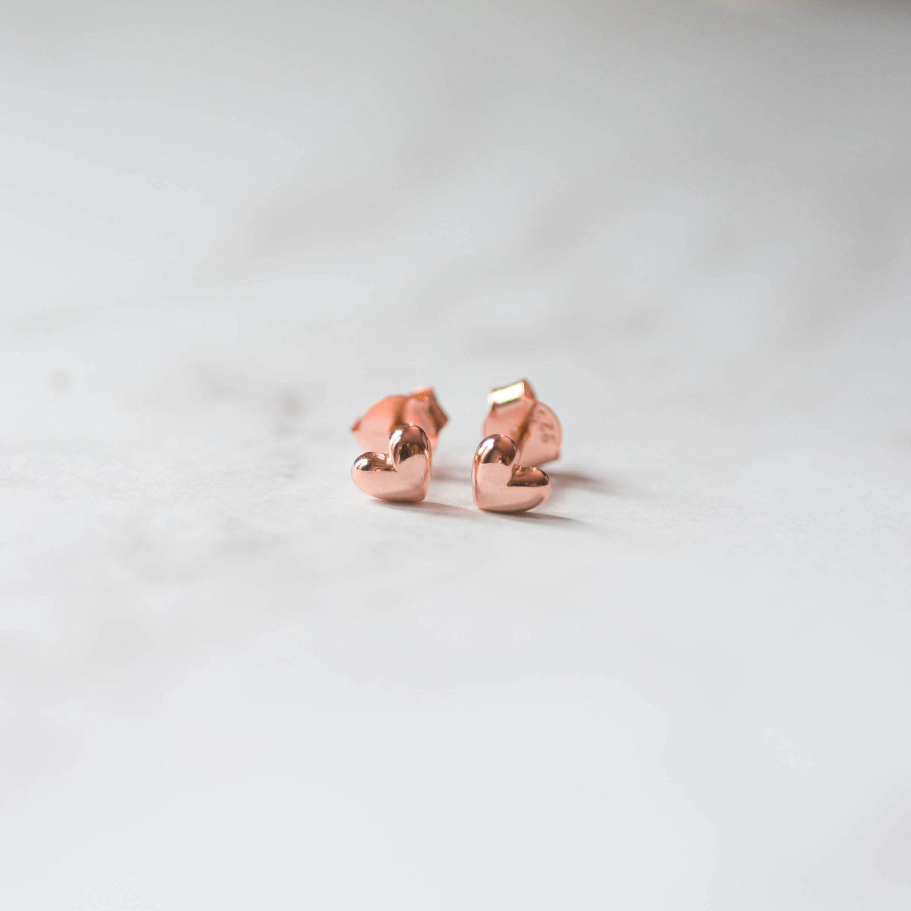 Rosegold plain heart stud earrings on marble background