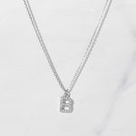 Silver studded letter necklace on marble background