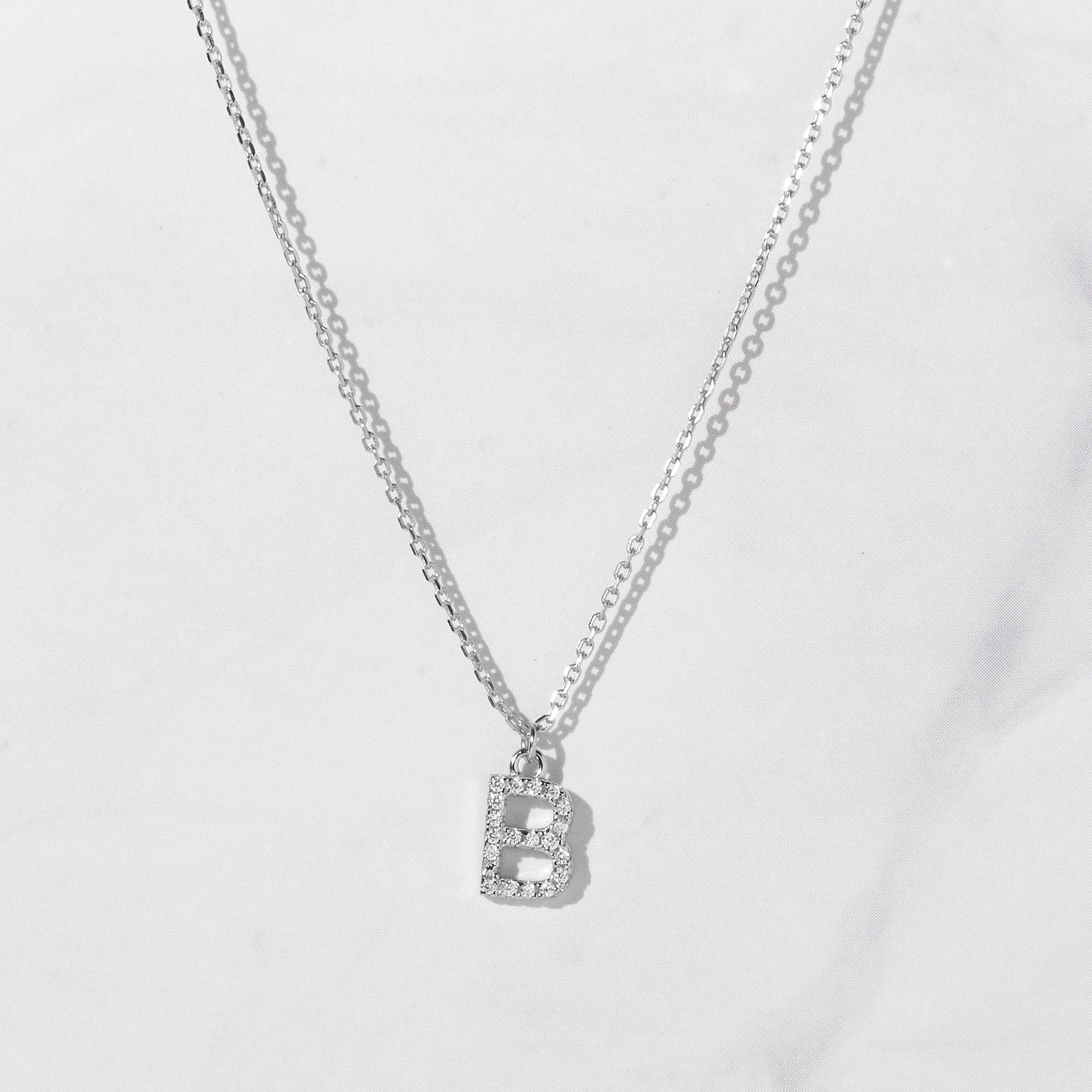 Silver studded letter necklace on marble background