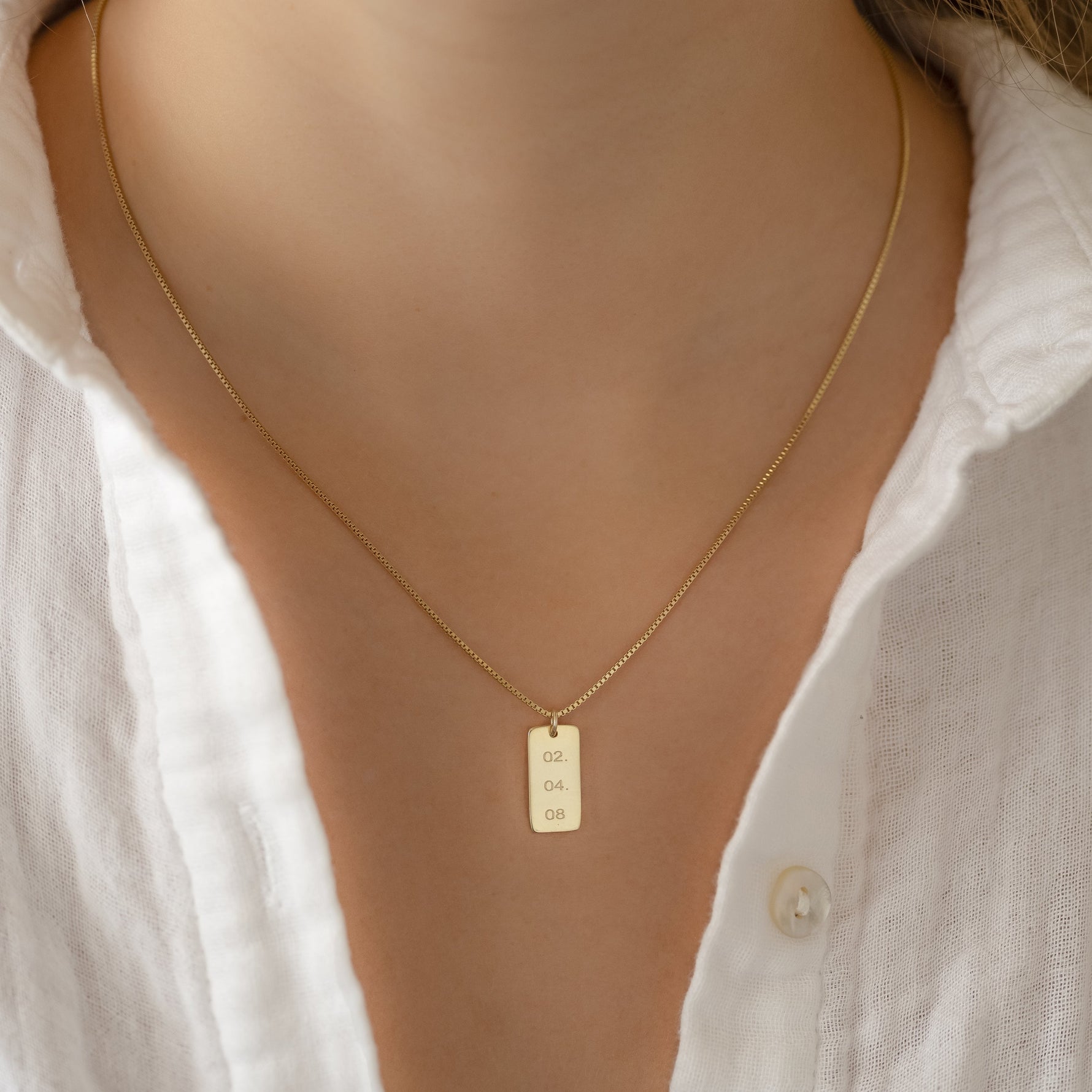Dainty gold important date necklace on a box chain seen on model
