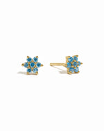Gold aquamarine birthstone flower studs on white background.