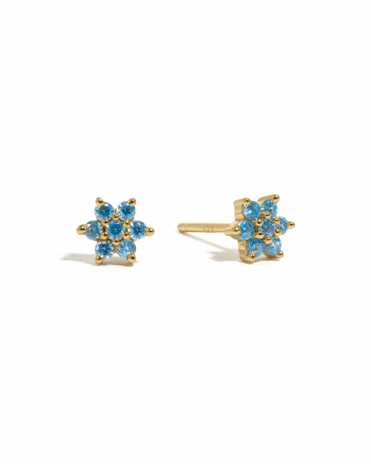 Gold aquamarine birthstone flower studs on white background.
