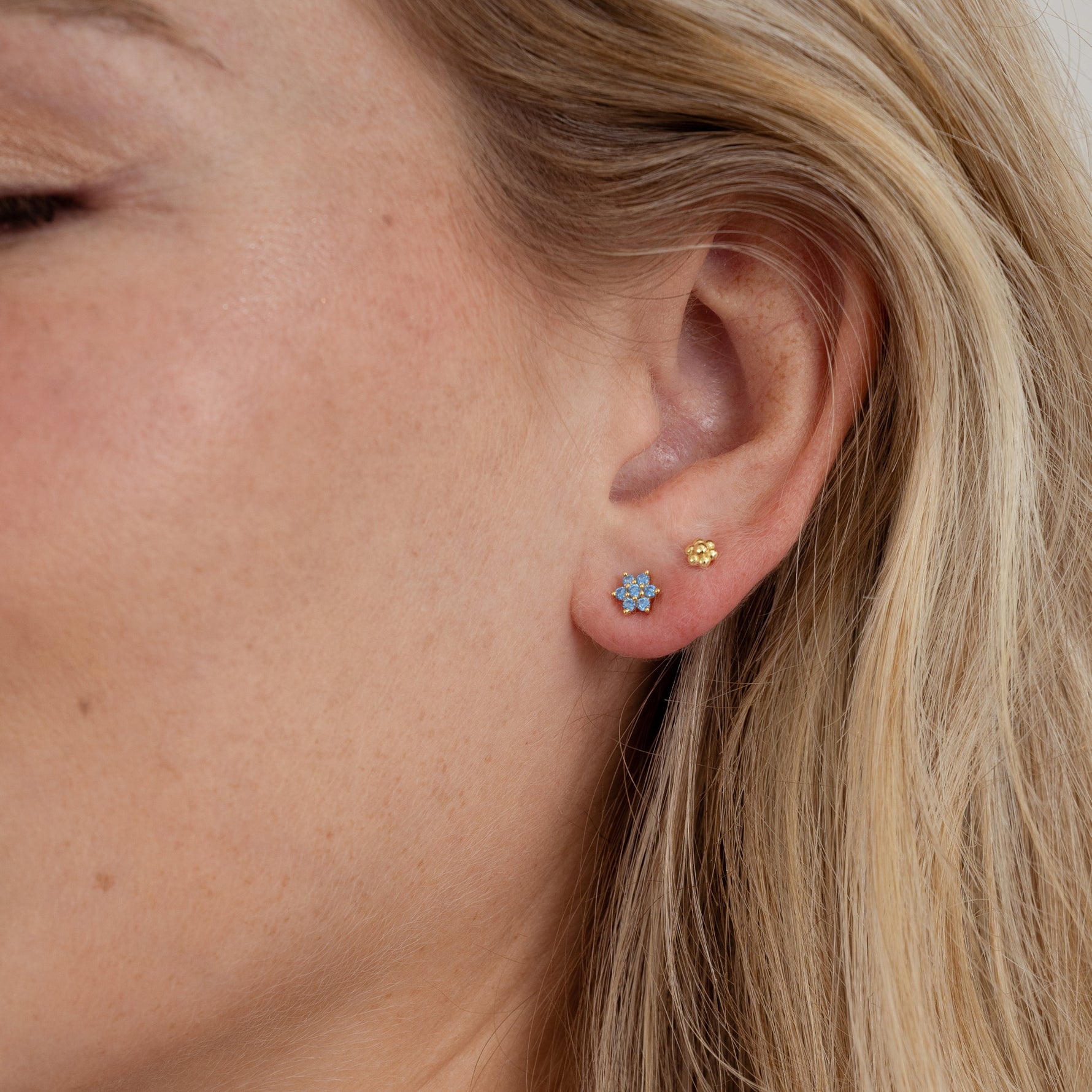 Model wearing gorgeous gold aquamarine flower stud earrings and tiny gold flower studs. 