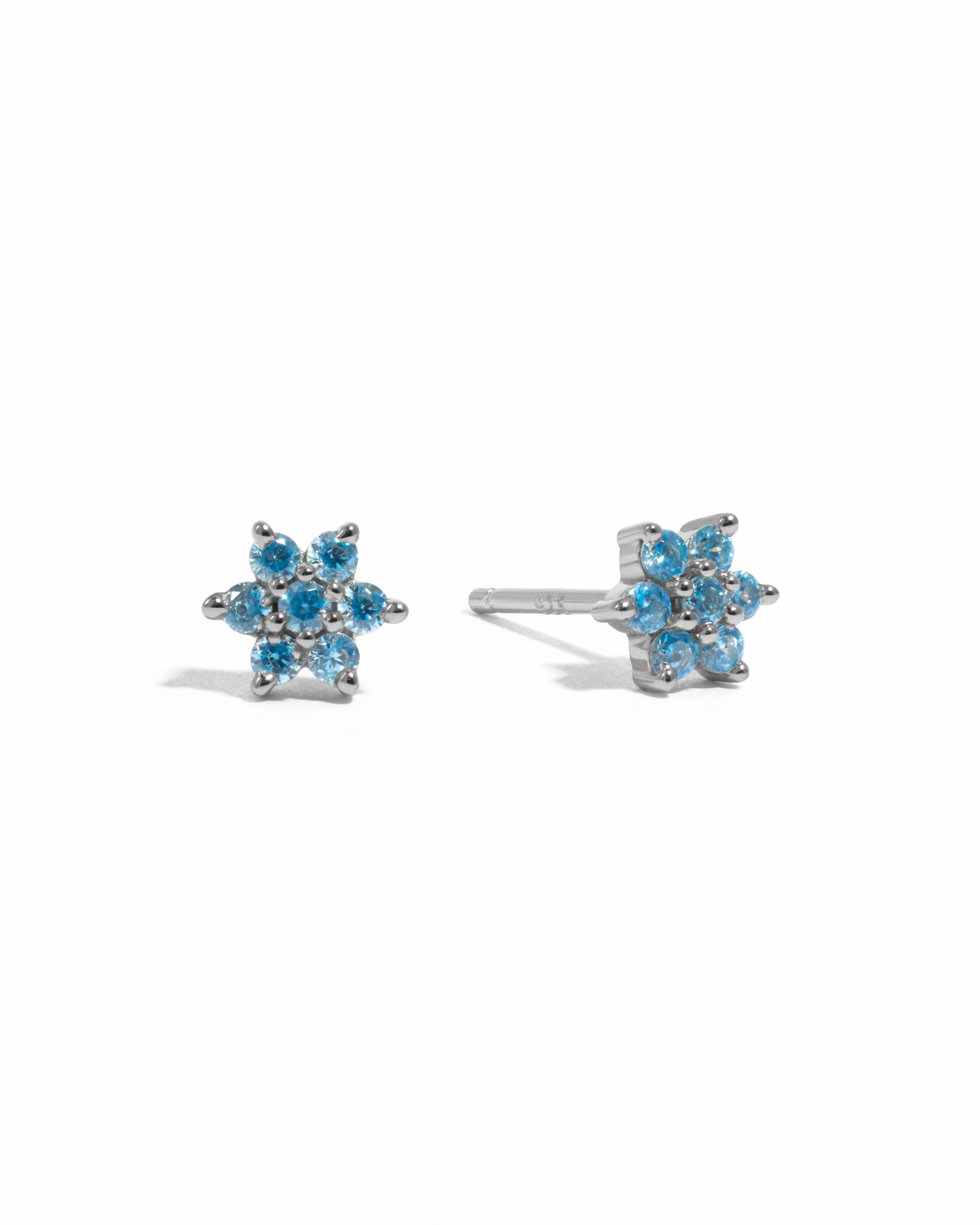 Sterling silver aquamarine birthstone flower studs on white background.